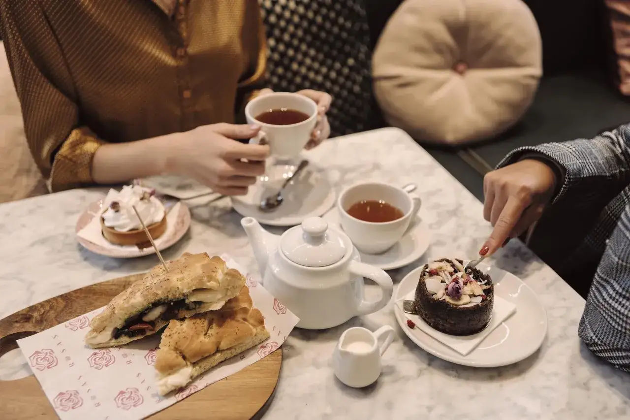 Två personer njuter av afternoon tea i Stockholm med te, bakverk och smörgåsar.